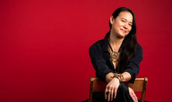 Andi Scull sitting against red backdrop - Austin Woman Magazine - by Daniel Nguyen