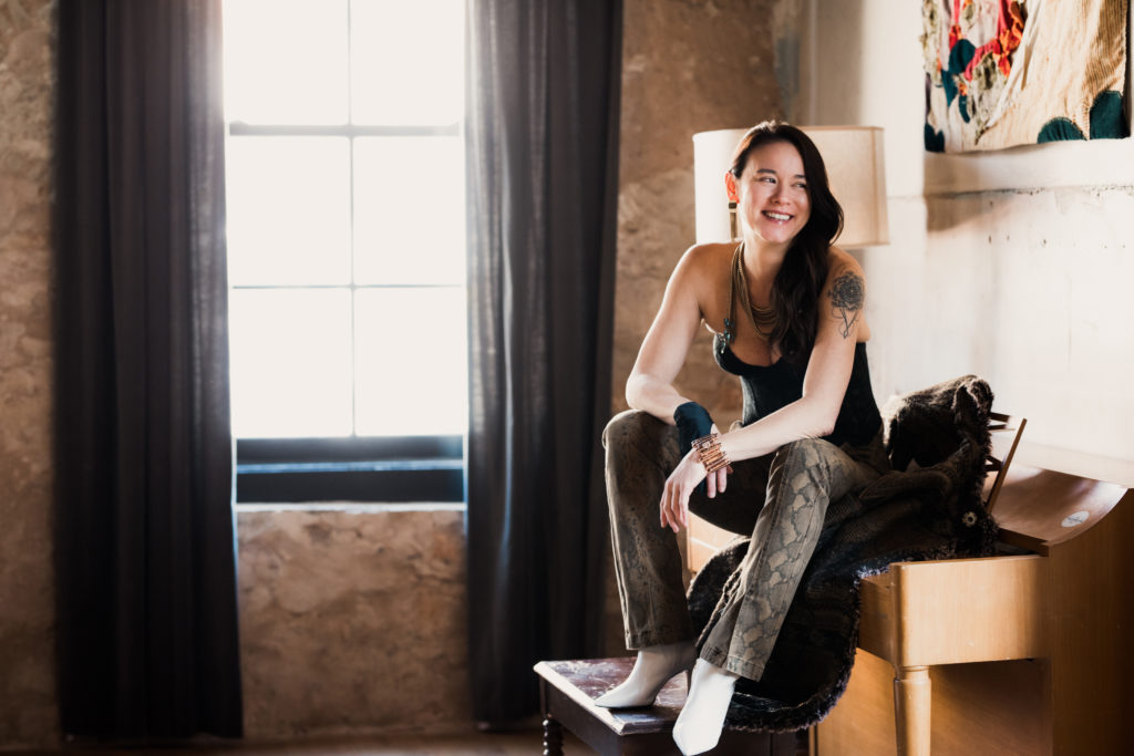 Andi Scull sitting on piano - Austin Woman Magazine - by Daniel Nguyen