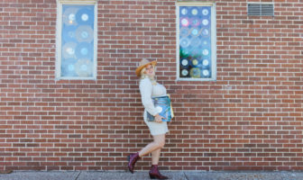 Cassie Shankman walking along brick wall - Austin Woman magazine - by Keelyn Costello