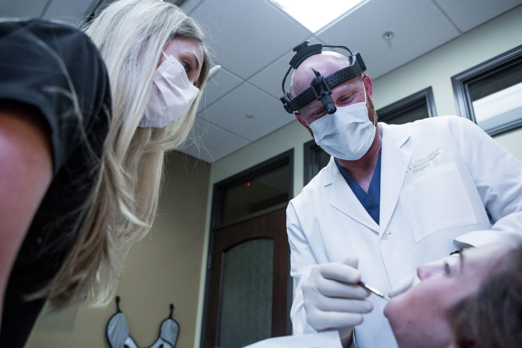 An oral surgeon inspects a patient's mouth.