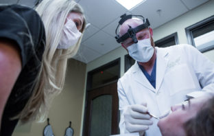 Oral Surgeon inspects a patient's mouth