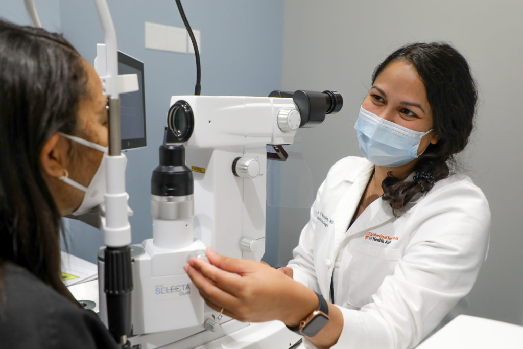 Woman checks another woman's eyes through medical device