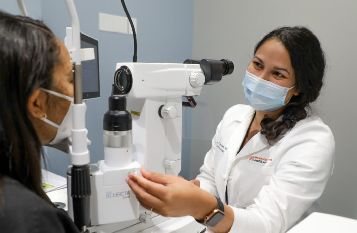 Woman checks another woman's eyes through medical device