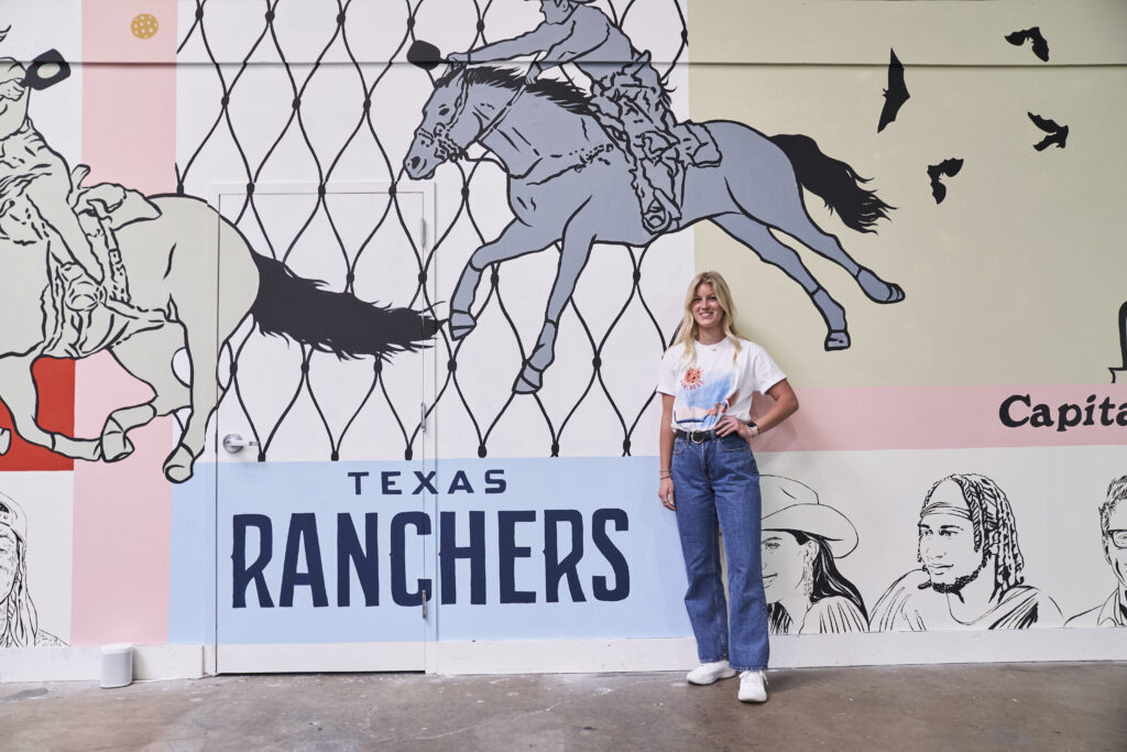 Alex Maxson, Texas Ranchers Head of Community and Operations, standing by mural