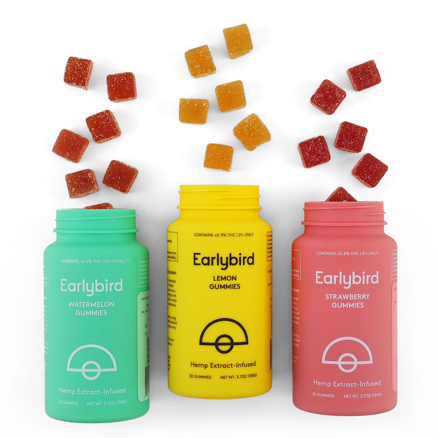 Picture of assotrment of Earlybird gummies from left to right; green bottle "watermelon gummies" with red-cubed gummies spilling out of the lid, yellow container "lemon gummies" with yellow-cubed gummies spilling out of the top and a pink container "strawberry gummies" with pink-cubed gummies spilling out of the top.