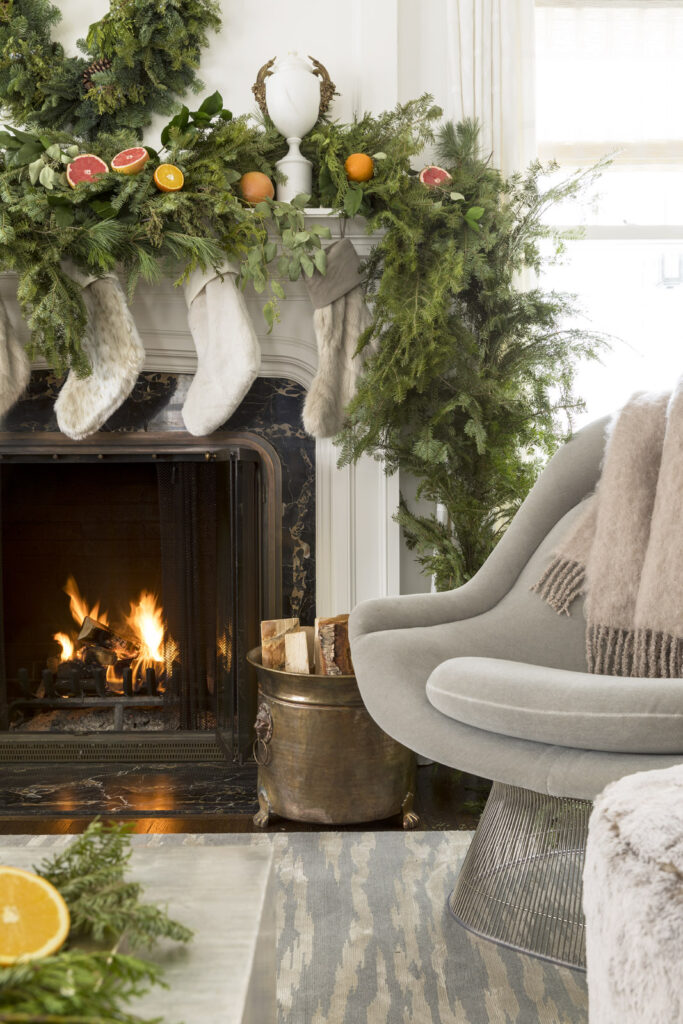 Close up of a fireplace mantle decorated with a leafy garland and white stockings. Antler decorations sit atop the mantle.