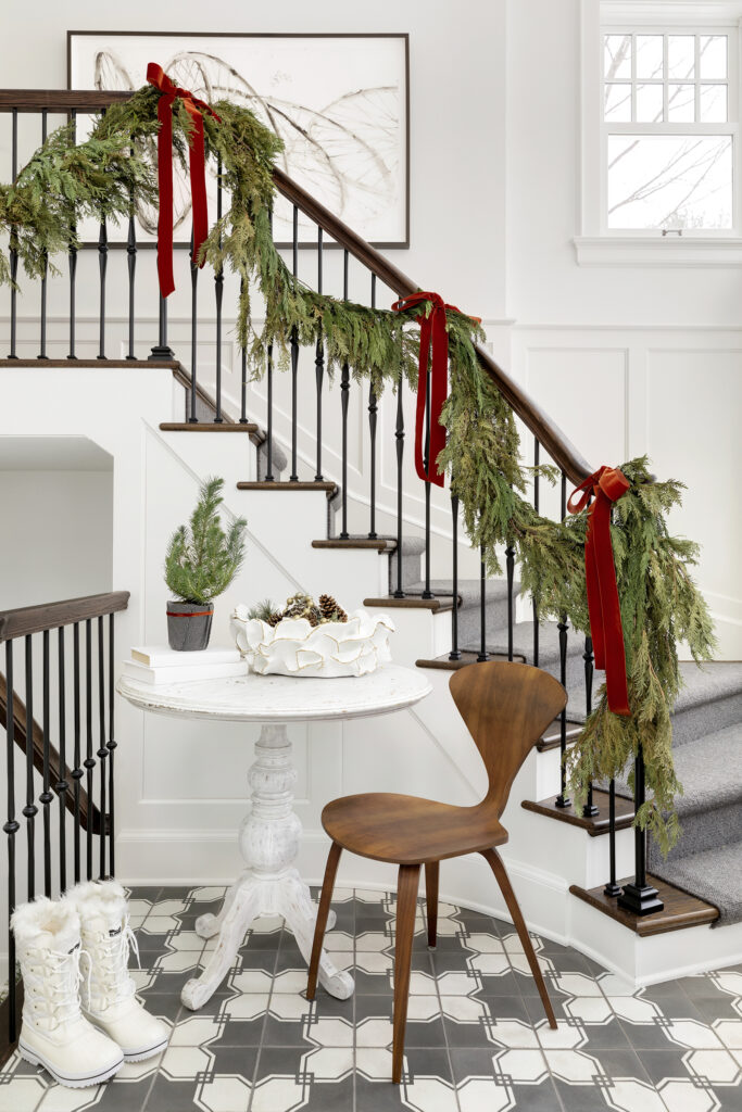 A staircase railing decorated with a leafy garland and red bows.